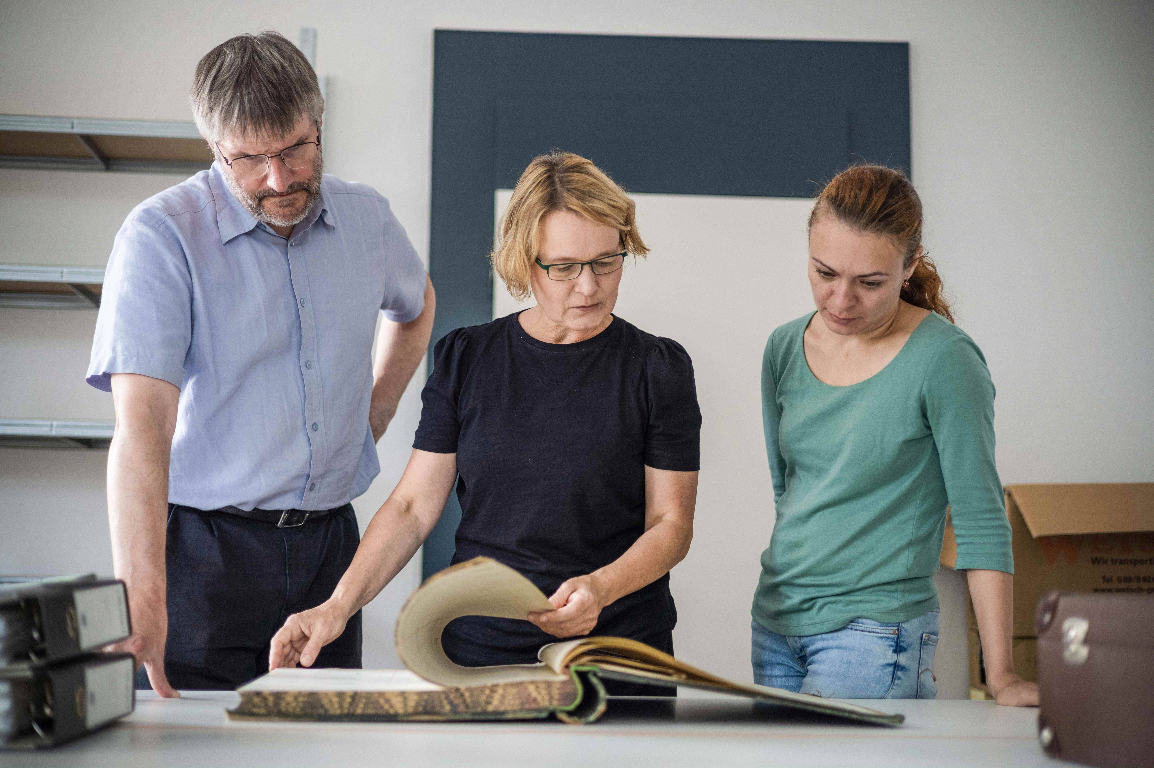 <p>Das Team analysiert gemeinsam ein Buch für Forschung oder Archivarbeit.</p>